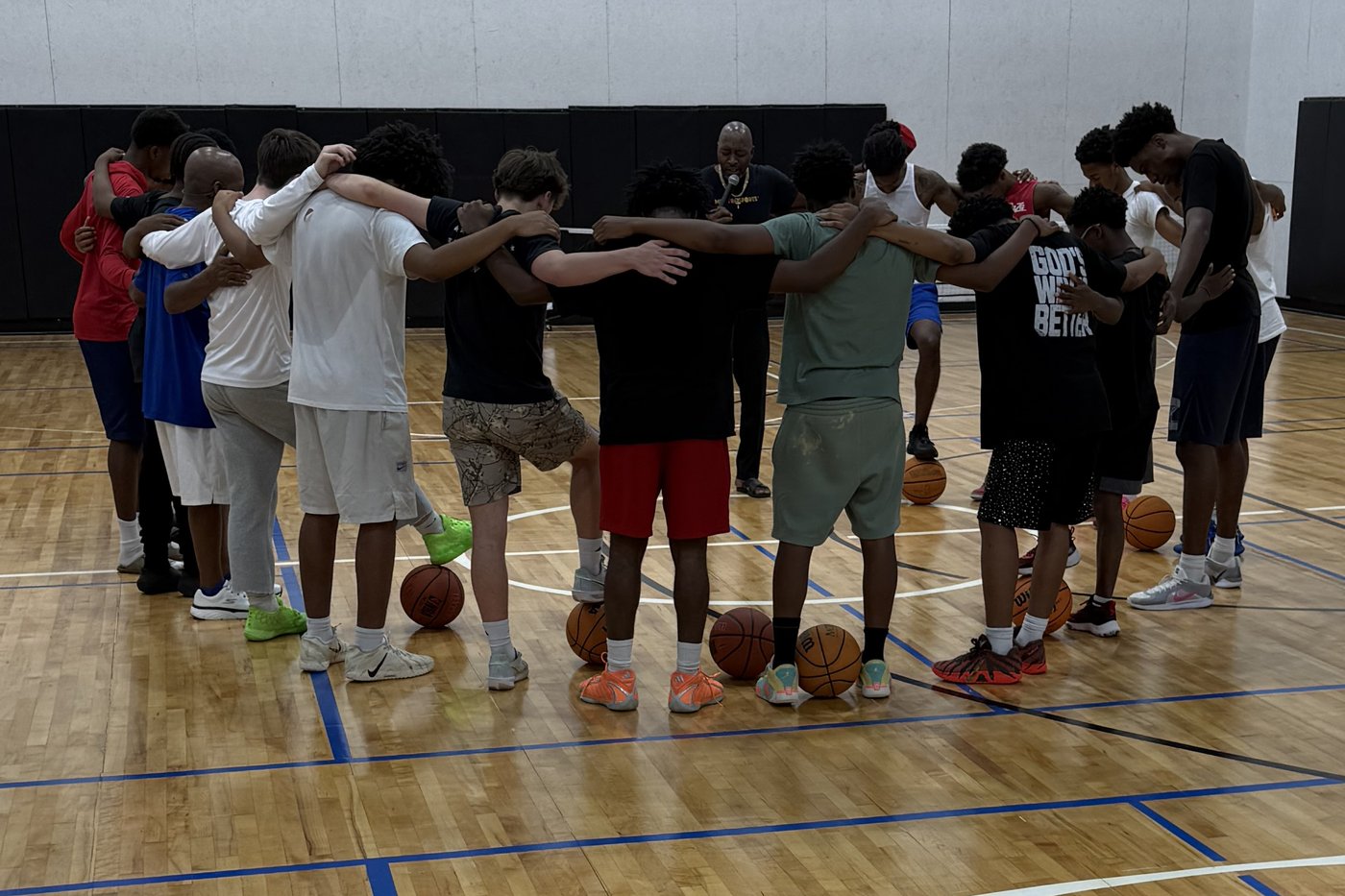 Young athletes and their coach in a team huddle on the MentorSports court